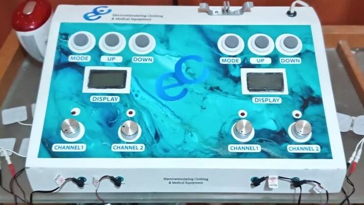 The two-channel electro-stimulation unit used in Joy of Giving rehabilitation sessions, with its electrode pads.